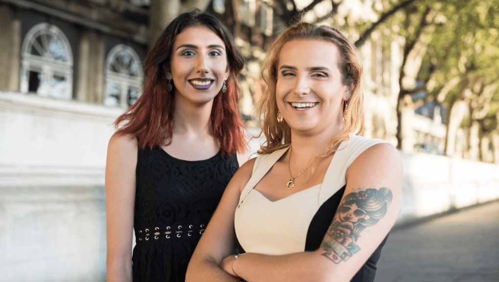 Two transgender people smiling at the camera.