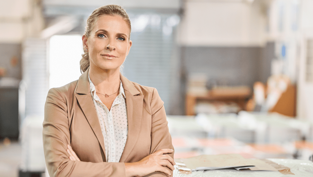 Woman in business professional clothing with hair pulled back looking at the camera with her arms crossed.